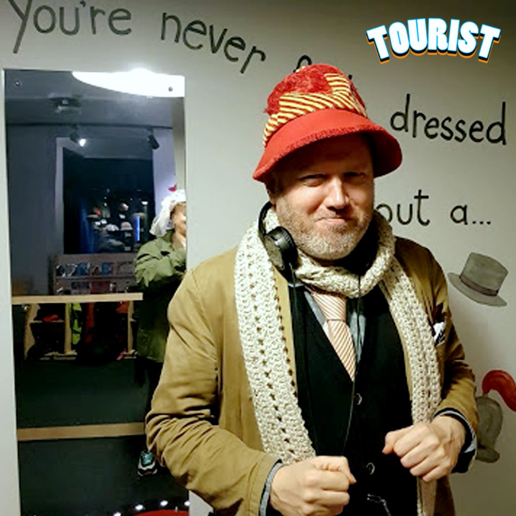 a photo of a man from the waist up. He is facing the camera and is wearing a red hat