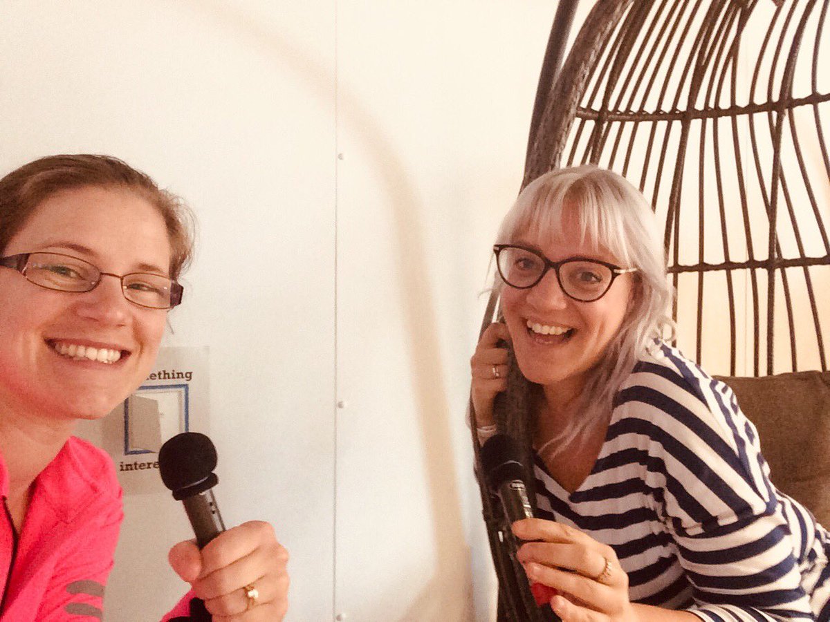 Image of a lady in a pink top holding a microphone smiling and Vic in a black and white striped top smiling