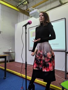 a woman is standing. She is speaking into a microphone